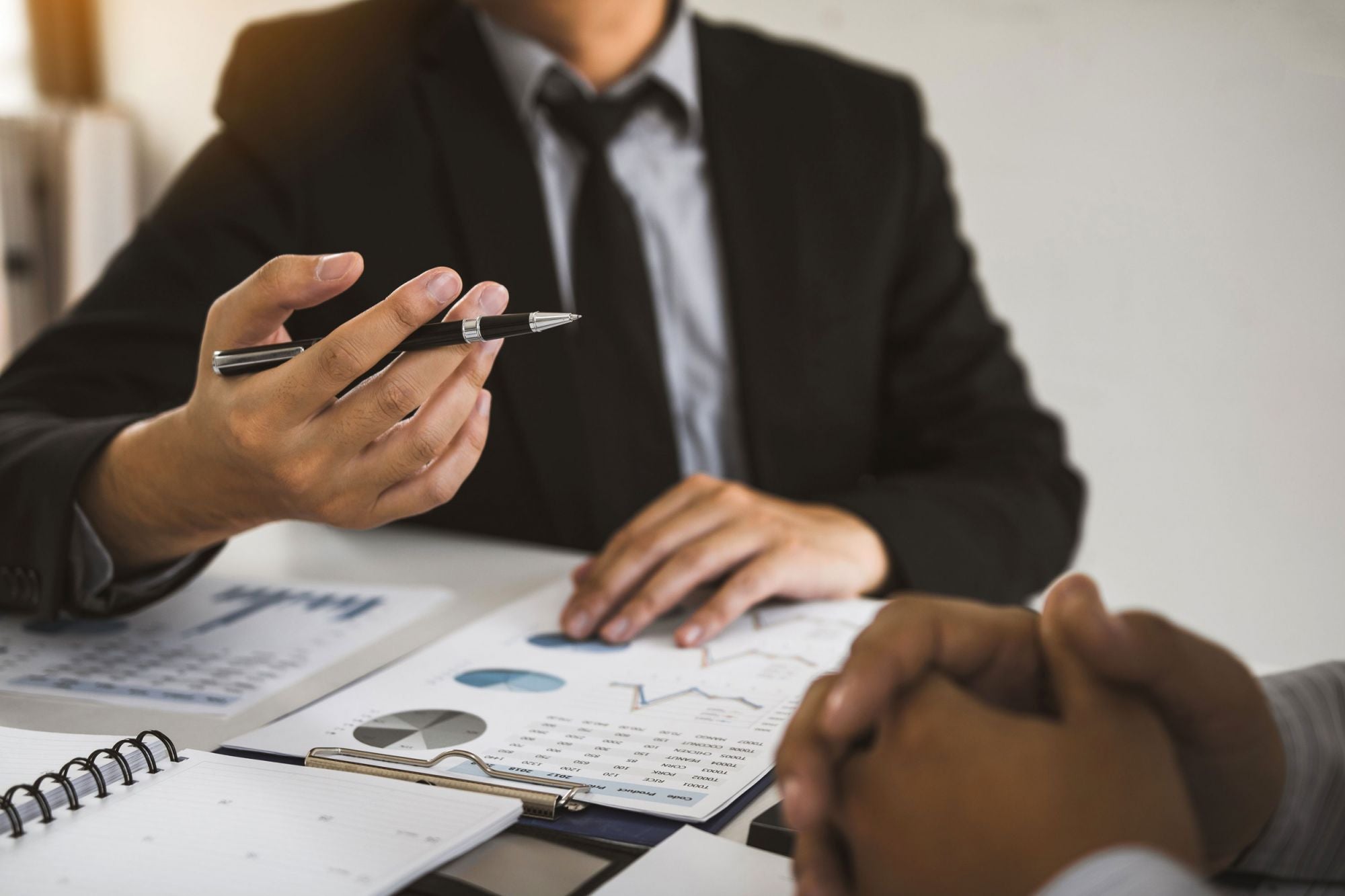 man holding pen explaining document to client