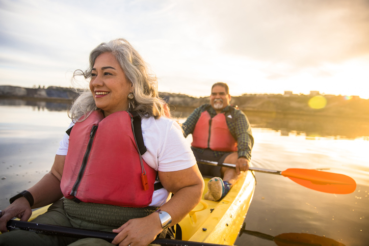 husband and wife sitting in a kayak on a lake at sunset
