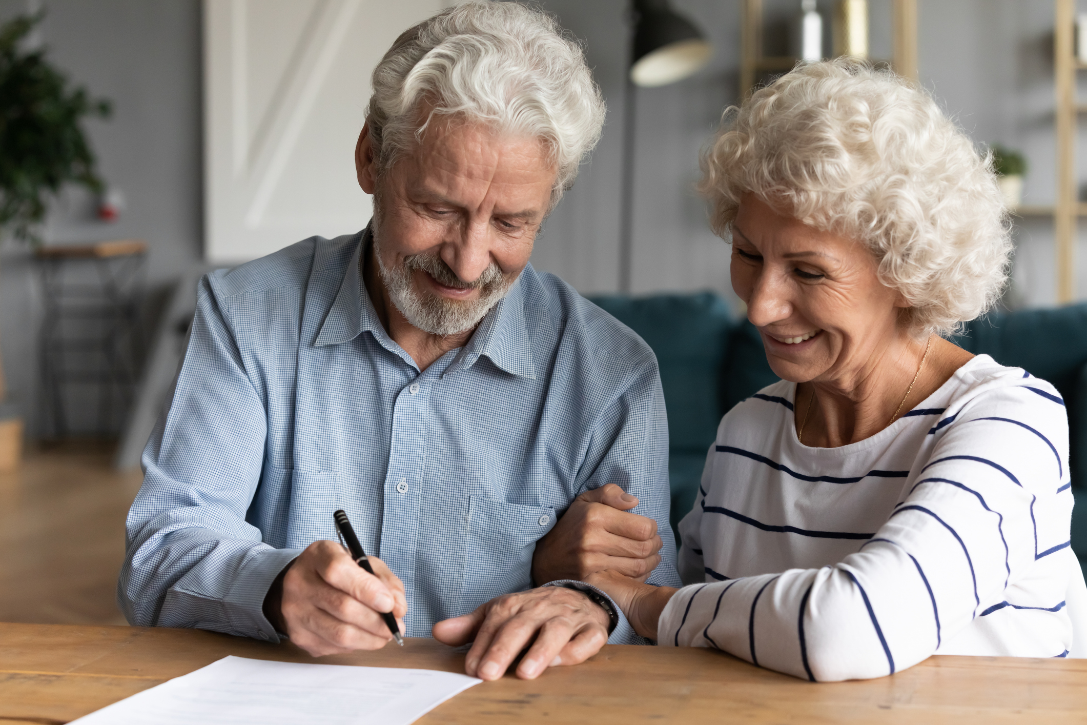 elderly couple signing retirement documents with a look of happiness on their faces