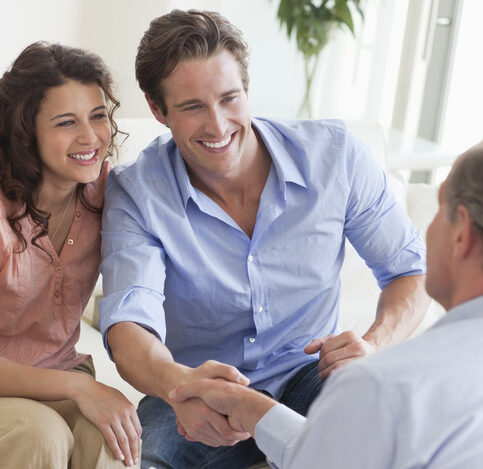 happy couple shaking hands with financial advisor